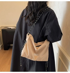 Close-up of beige nylon messenger bag with thick black and white rope strap detail
