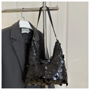 Detail view of a black sequin dumpling shoulder bag hanging on a rack with a sleek finish