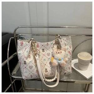 Détail d'un cabas floral blanc avec imprimé ours et breloque peluche sur étagère