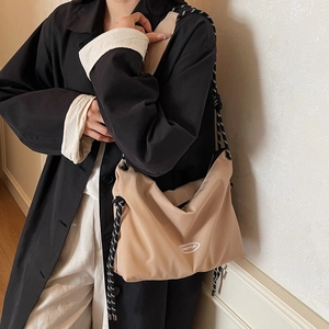 Minimalist beige large capacity crossbody bag with woven rope strap on black coat