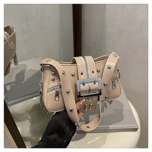 Detail of beige faux leather bag with silver metal rivets and wide buckle strap design