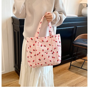 Detailed close-up of pink corduroy tote bag with strawberry prints and double handles