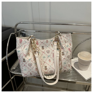 Detail of white quilted tote bag featuring cute bear prints and gold chain strap