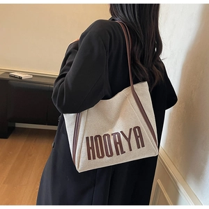 Lifestyle shot of large oatmeal canvas tote bag with brown leather trim worn by model