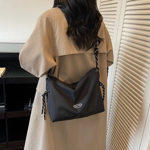 Japanese style black nylon crossbody bag with woven rope strap shown on a trench coat