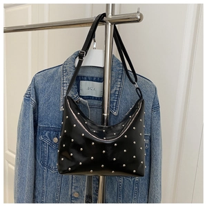 Detail of black glossy bucket bag featuring silver rivets and adjustable shoulder strap