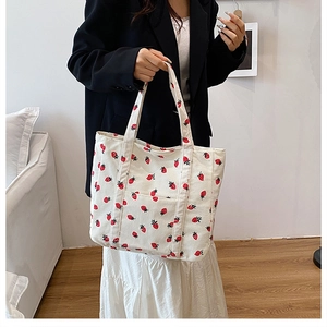 Detail of strawberry print corduroy tote bag showing soft texture and front pocket