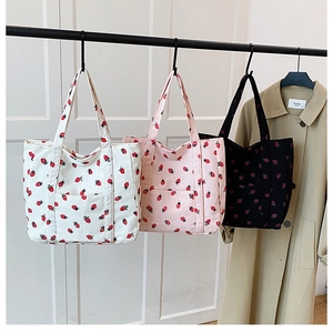 Detail of strawberry print corduroy tote bags in cream, pink and black colors