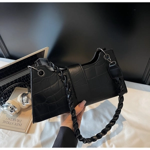 Close-up of black crocodile embossed faux leather bag with spiral handle texture