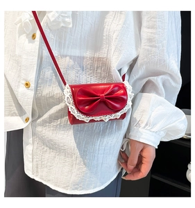 Detail of red square crossbody bag with large leather bow and white lace trim