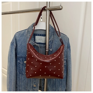 Close-up of deep red crescent bucket bag featuring silver stud details and leather texture