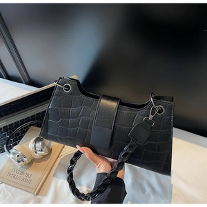 Detail of black crocodile texture baguette bag with thick chain handle and metal buckle