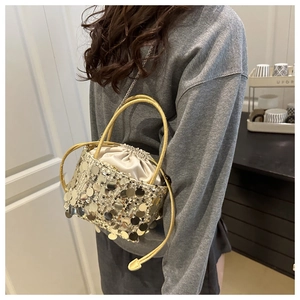Detailed close-up of a luxury gold sequin bucket bag with drawstring and chain strap