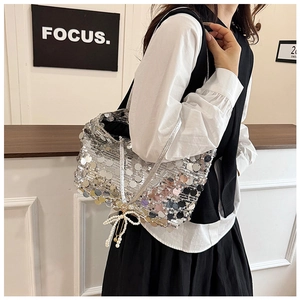 Close-up of silver sequin shoulder bag with pearl bow charm and sleek metallic strap