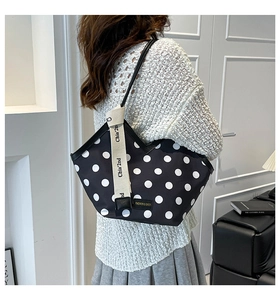 Polka dot tote bag with lettered straps shown on shoulder for size reference