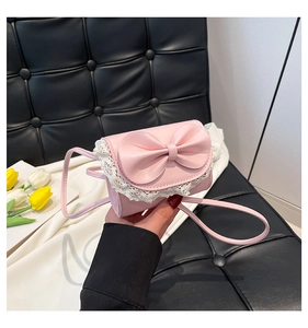Close-up of pink mini crossbody bag with a large bow and white lace trim detail