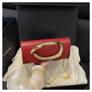Detail of red leather crossbody bag with gold oval buckle handle in luxury gift box