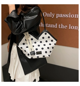 Close-up of polka dot tote bag with V-shaped cut and wide branded textile strap