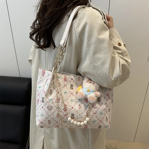 Gesteppte rosa Bär-Tasche mit Perlenkette und Plüsch-Anhänger an einem weiblichen Modell