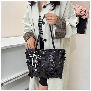 Detail of black sequin tote bag featuring a pearl bow charm and tassel detail
