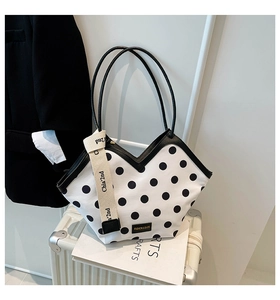 Close-up of black and white polka dot bucket bag with gold metal logo and stylish V-cut top