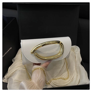 Detail view of white leather crossbody bag with gold handle in a black luxury gift box