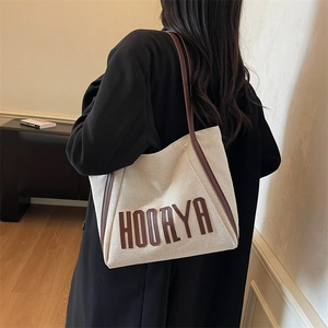 Minimalist canvas tote bag with leather trim and HOORYA letter patch in a high-capacity design