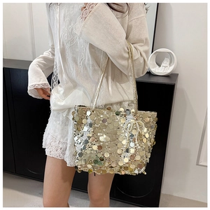 Detailed shot of golden sequin tote bag featuring pearl bead accessory on a white strap