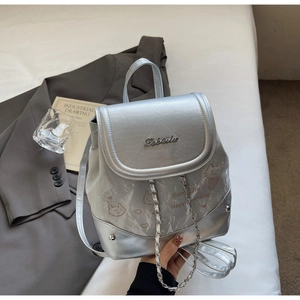 Detail of silver metallic mini backpack featuring cartoon prints and decorative metal chain