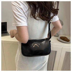 Gros plan sur le sac à bandoulière en cuir noir avec boucle nœud doré et sangle large