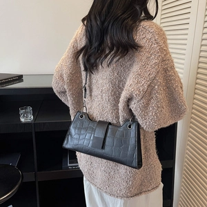 Chic black crocodile pattern baguette bag with shoulder strap in a stylish indoor setting