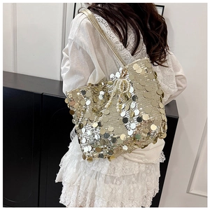 Macro detail of golden sequin tote bag with a pearl bow pendant and metallic shine