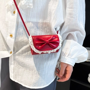 Fashionable red square crossbody bag with white lace trim and bow accent on model