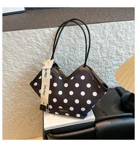 Close-up of black and white polka dot tote bag with V-shaped neck and ribbon detail