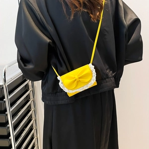 Back view of a yellow mini crossbody bag with white lace trim and bow on a model