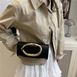 Minimalist black rectangular crossbody bag featuring oversized gold oval ring and chain