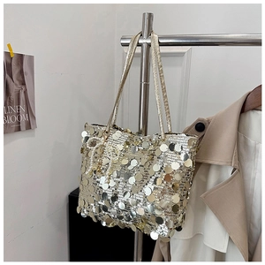 Detail of silver gold sequin tote bag featuring large discs and a pearl bow charm