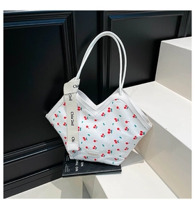 Detail of white nylon tote bag featuring red cherry prints and decorative ribbon