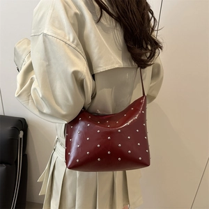 Vintage burgundy hobo bag with silver studs shown from a side perspective on model