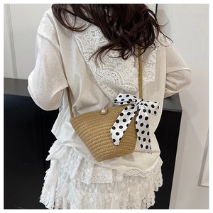 Détail du sac seau en paille avec fermoir perle et nœud en ruban à pois noir et blanc