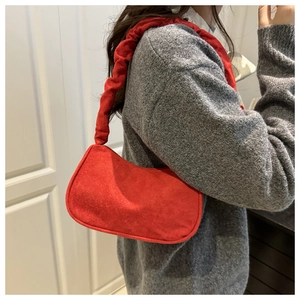 Détail du sac à bandoulière en daim rouge montrant la texture velours et l'anse froncée