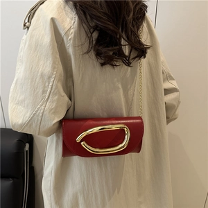 Modern red leather crossbody bag with oversized gold metal buckle and chain strap