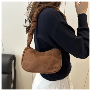 Détail du sac en faux daim marron avec anse plissée porté par le modèle