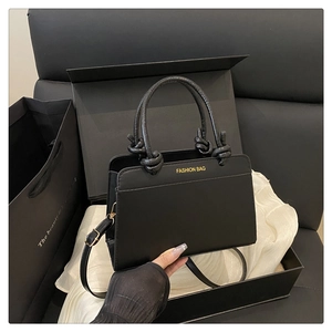 Detail of black crossbody bag with gold text in a premium gift box packaging