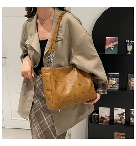 Detail of a brown tote bag with vintage monogram print and silver chain strap on shoulder