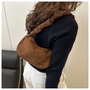 Détail du sac sous le bras en daim marron avec une bandoulière plissée au design texturé