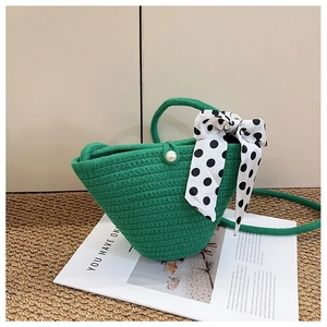 Détail du sac seau tressé vert avec un nœud en ruban à pois et un fermoir en perle