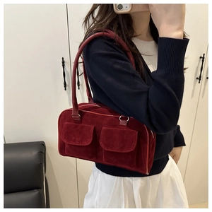 Detail of burgundy suede shoulder bag with dual front pockets and top handles