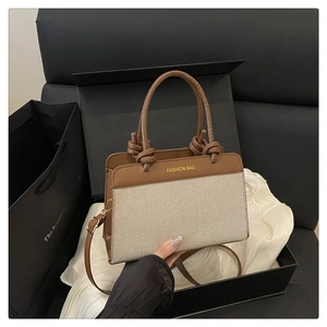 Detail of canvas and leather handbag with braided handle inside a gift box