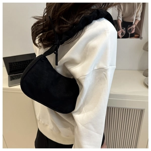 Détail d'un sac à bandoulière noir plissé montrant le nœud unique sur la lanière